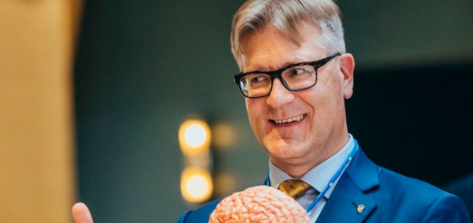 Puhuja ja kouluttaja Niko Visuri luennoimassa kädessään muoviset ihmisaivot.
